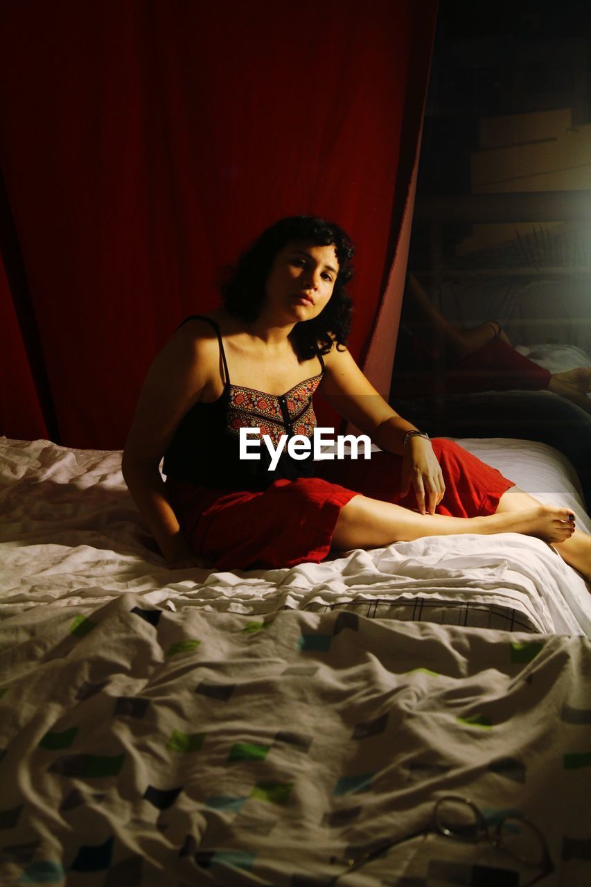 Portrait of young woman sitting on bed