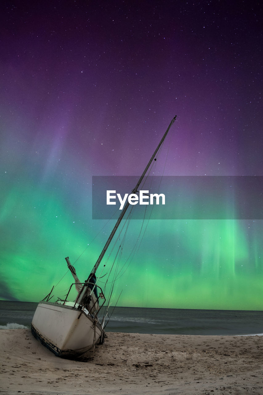 Aurora borealis over a shipwreck off the coast of uttakleiv beach in norway