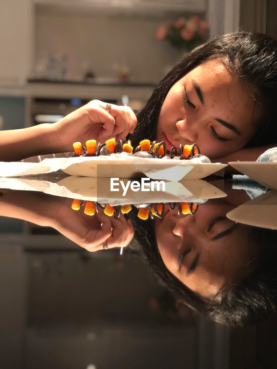 Young woman with food lying on table at home