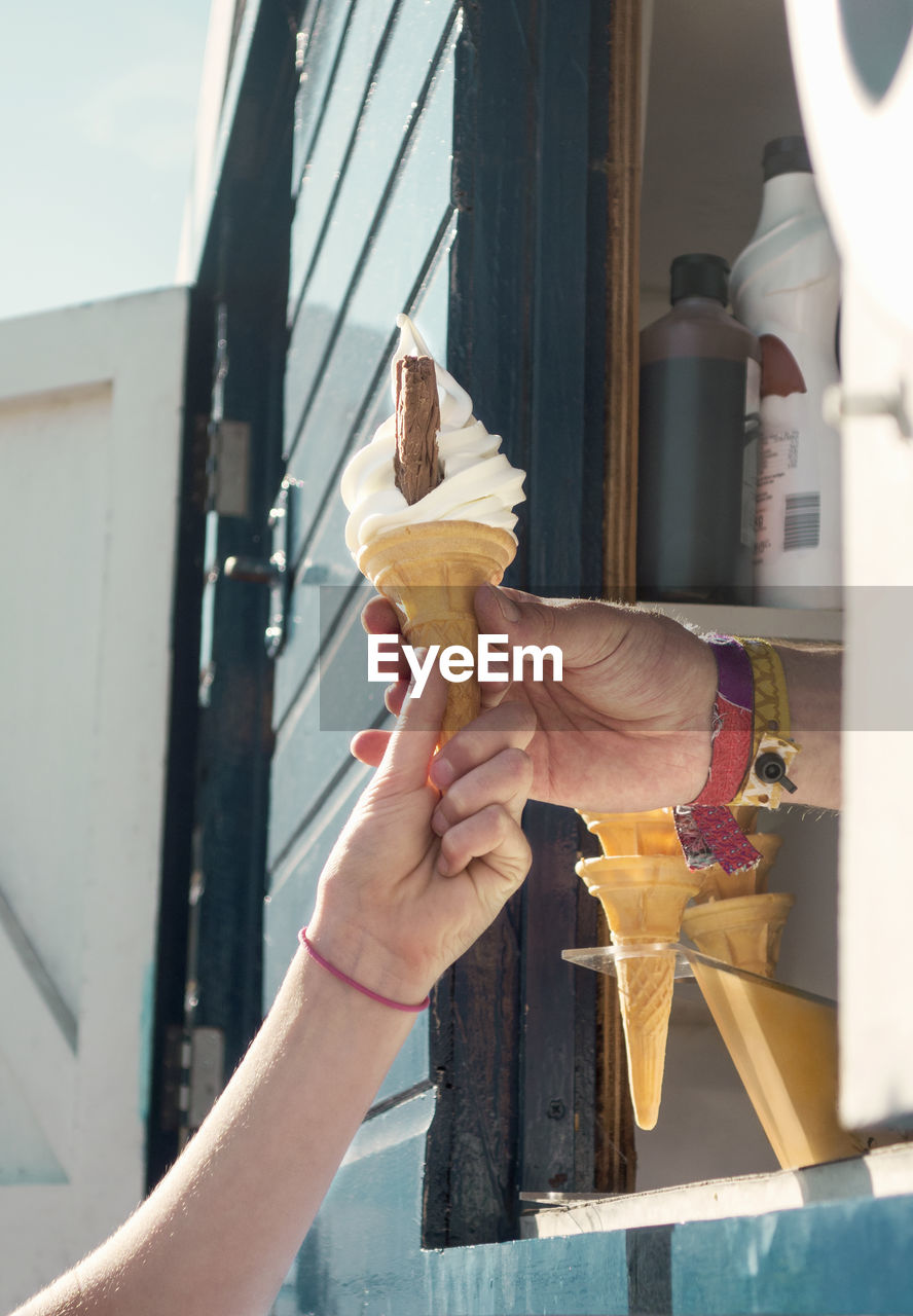 Close-up of hand holding ice cream on sunny day