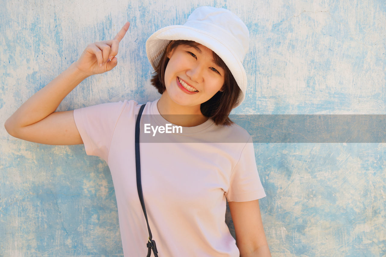 Portrait beautiful woman wearing hat standing against wall