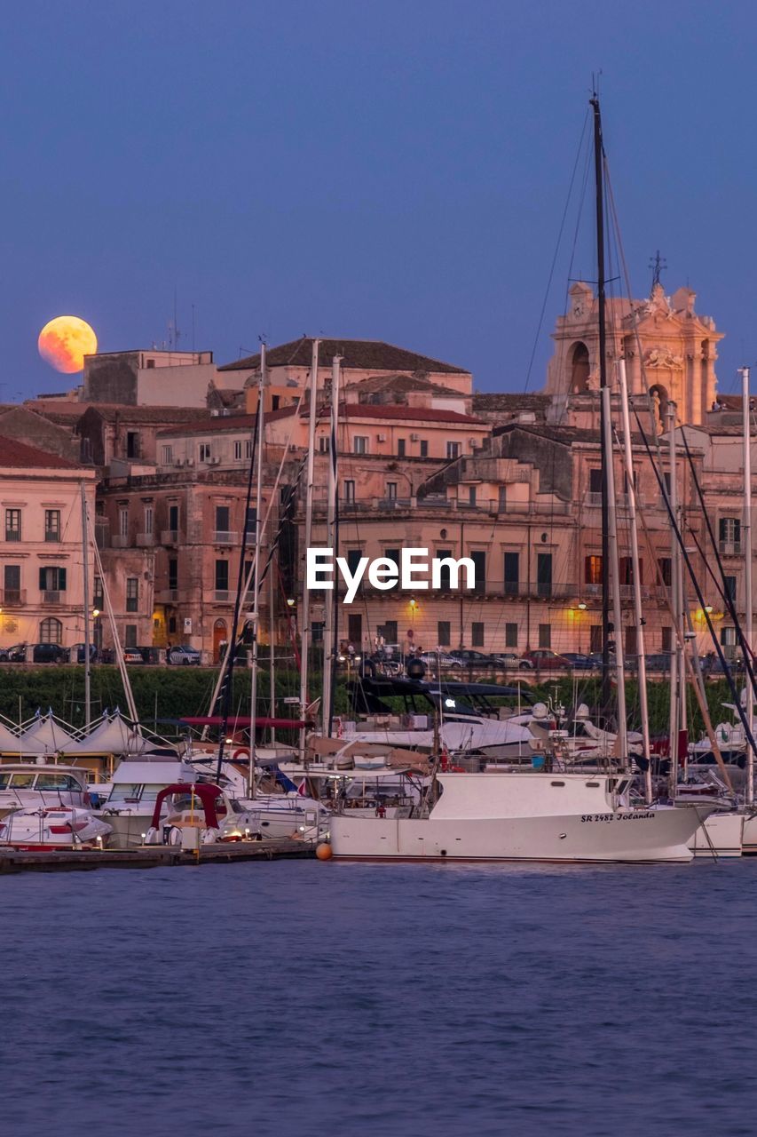 SAILBOATS IN SEA BY BUILDINGS AGAINST SKY