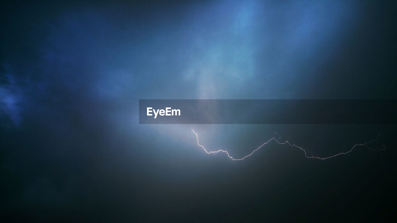 Low angle view of lightning against cloudy sky at night