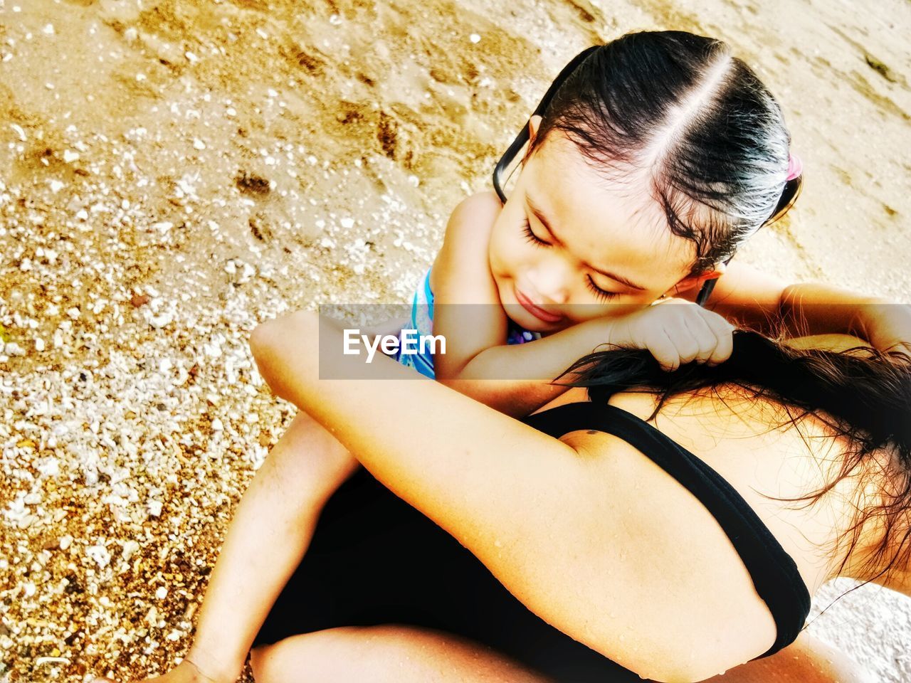 High angle view of mother piggybacking daughter at beach