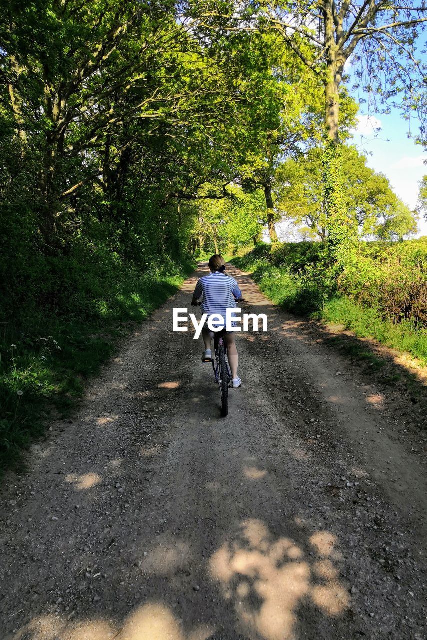 REAR VIEW OF PERSON RIDING BICYCLE
