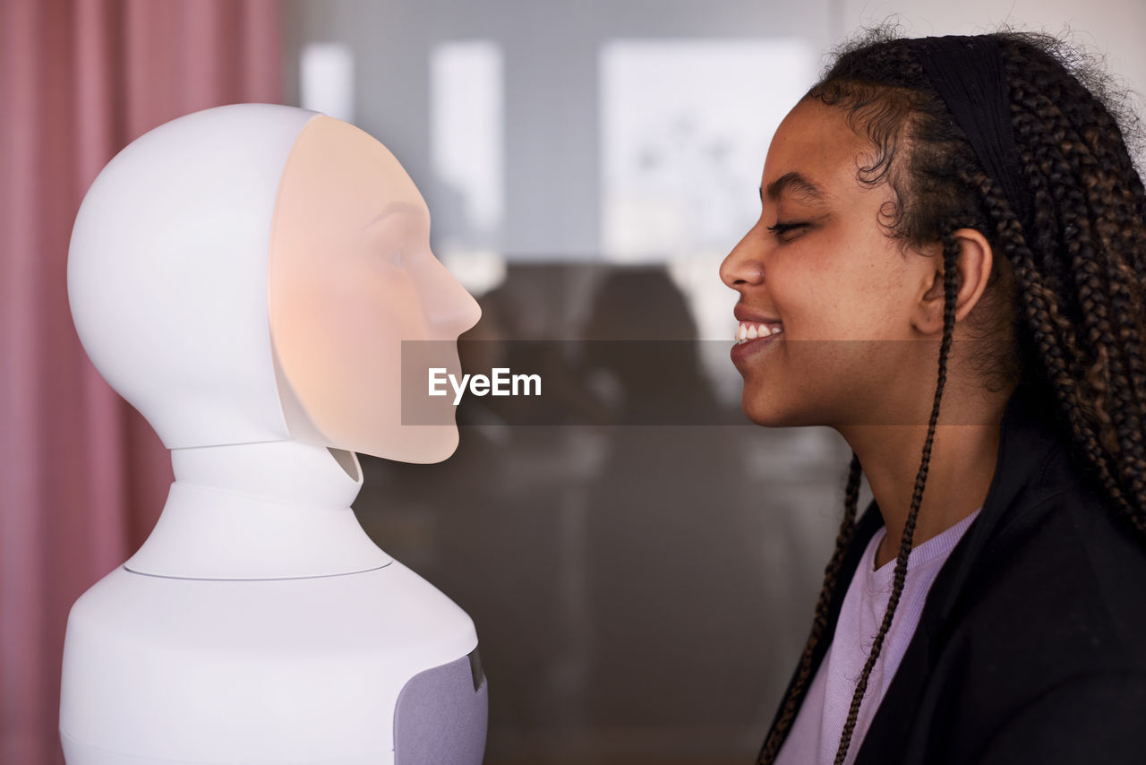 Young woman looking at robot voice assistant