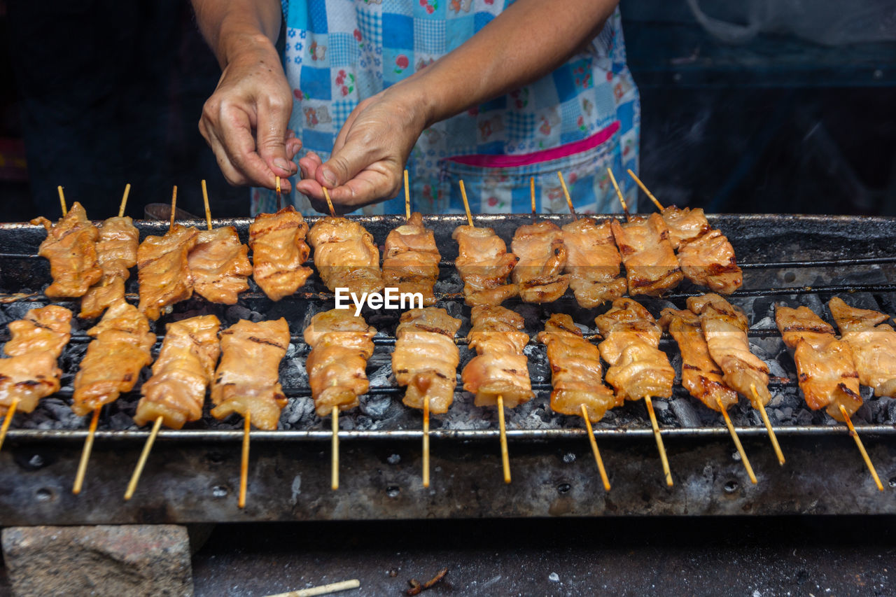 cropped hand of man preparing food on barbecue grill