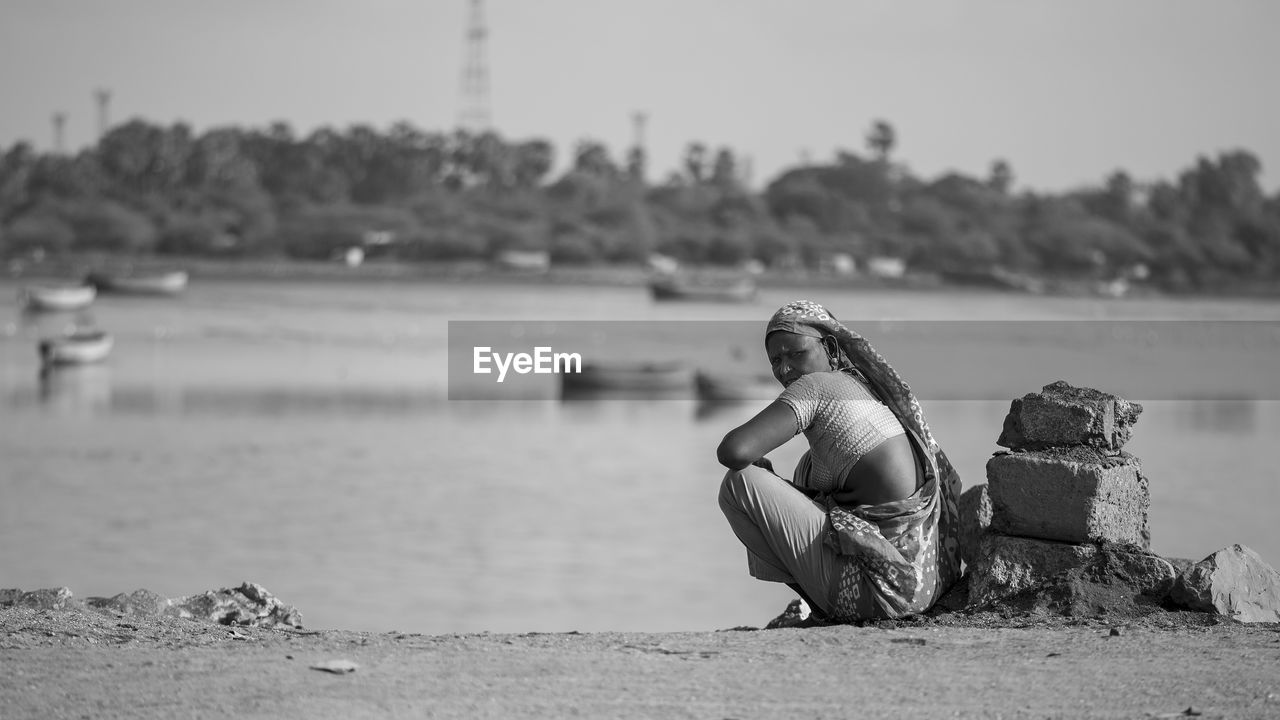 Woman crouching at riverbank