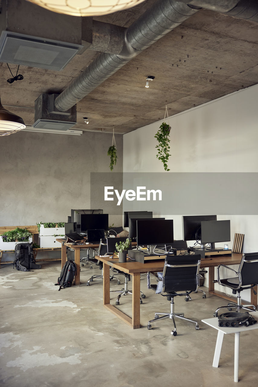 Computers on desks with chairs in creative office