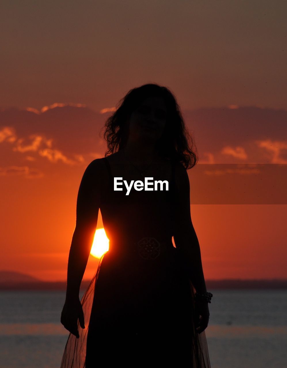 Woman standing at beach during sunset