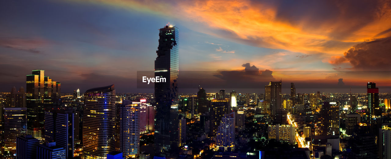 ILLUMINATED MODERN BUILDINGS IN CITY AGAINST SKY