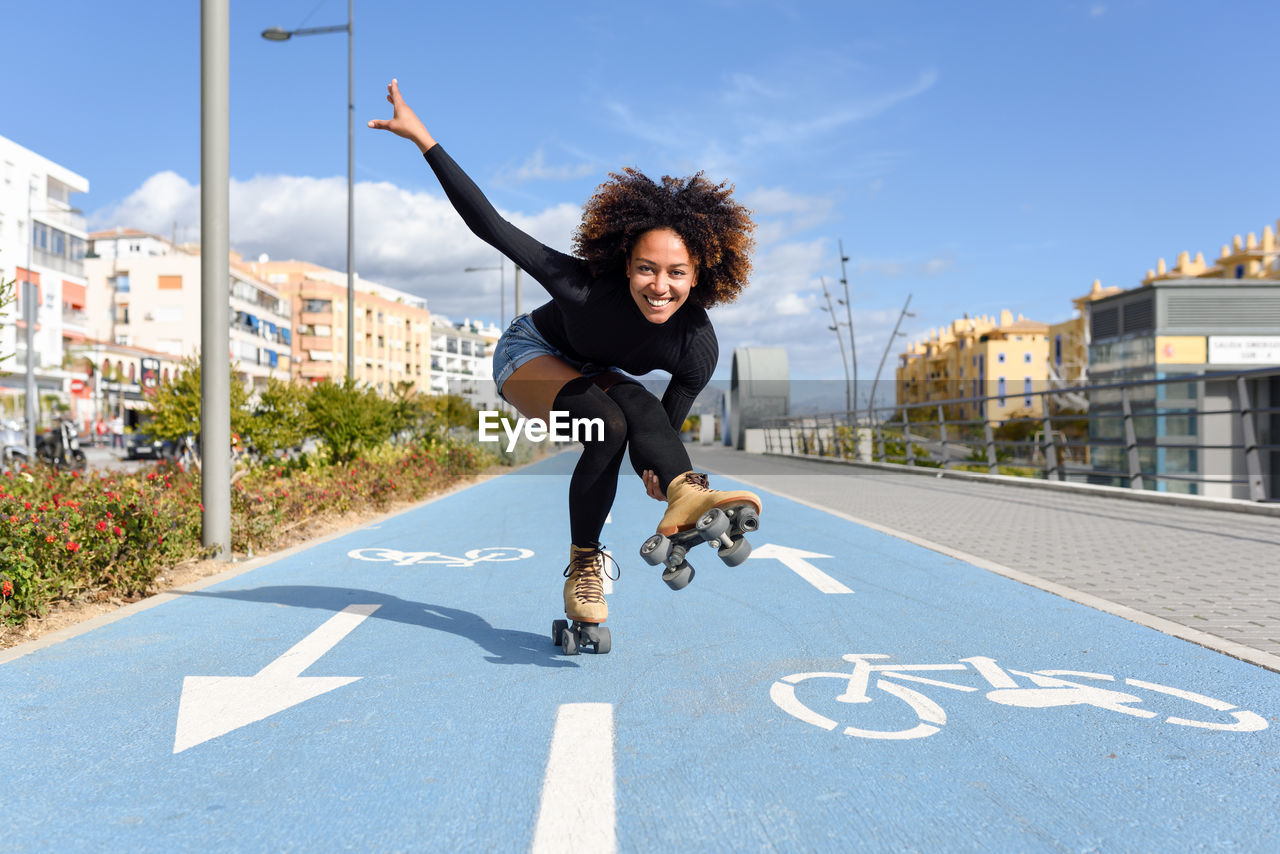 Full length of young woman with roller skates on road against sky