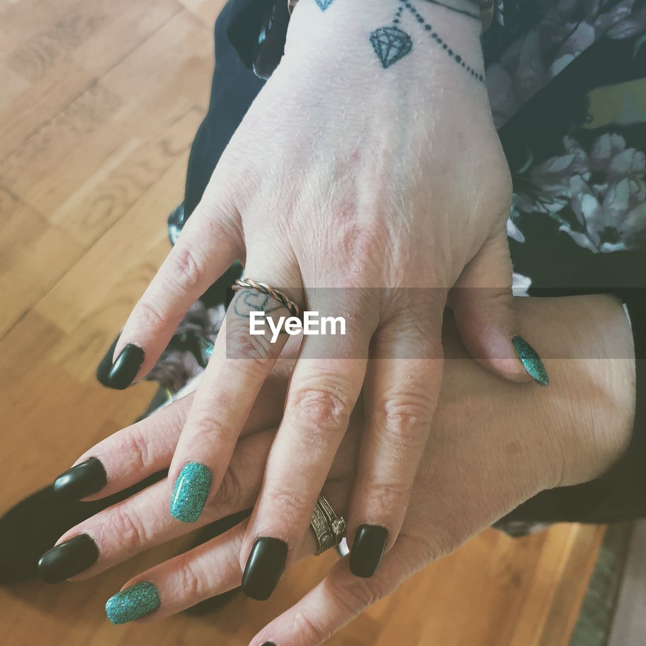 HIGH ANGLE VIEW OF HANDS OF WOMAN WITH TATTOO ON TABLE