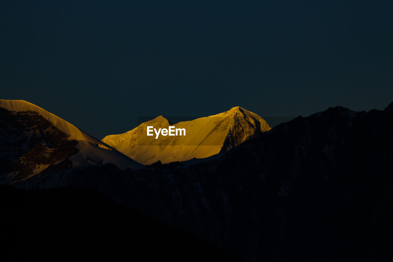 Scenic view of snowcapped mountains against clear sky at night