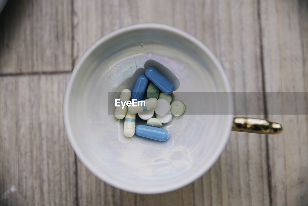 Directly above shot of medicines in cup on table