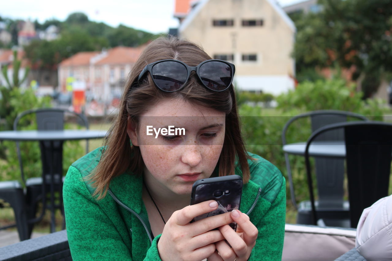 Woman using phone at outdoor restaurant