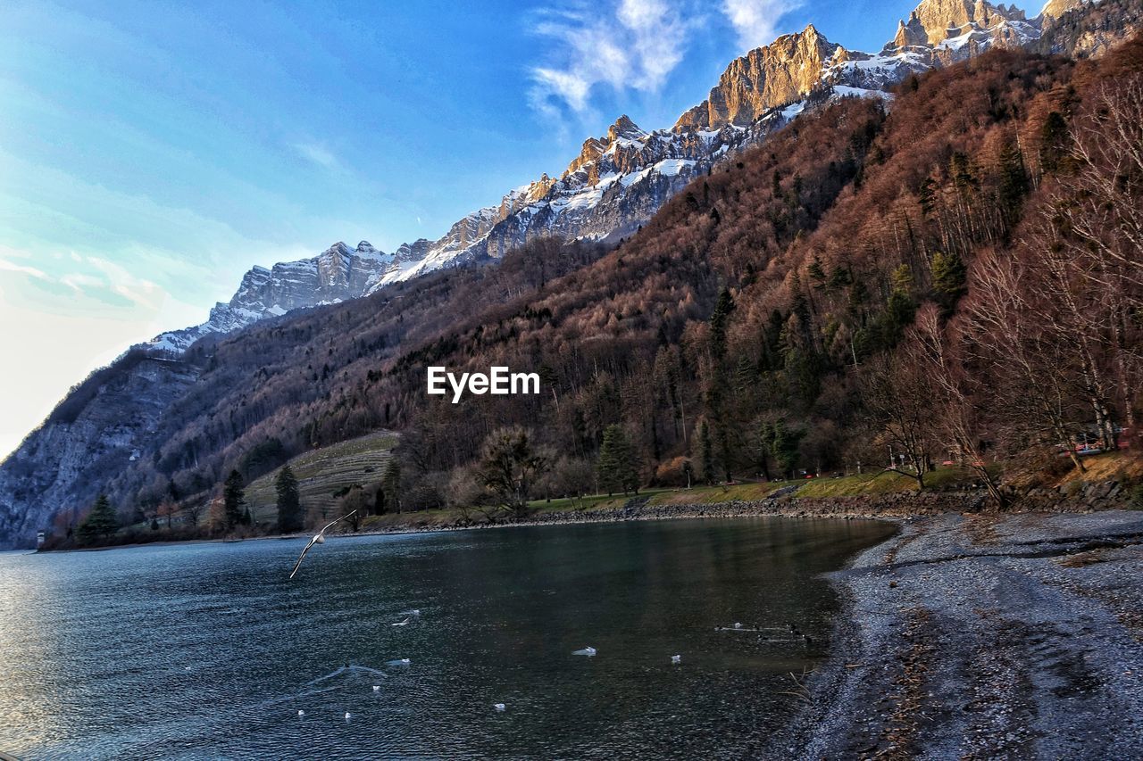 Scenic view of lake by mountains against sky