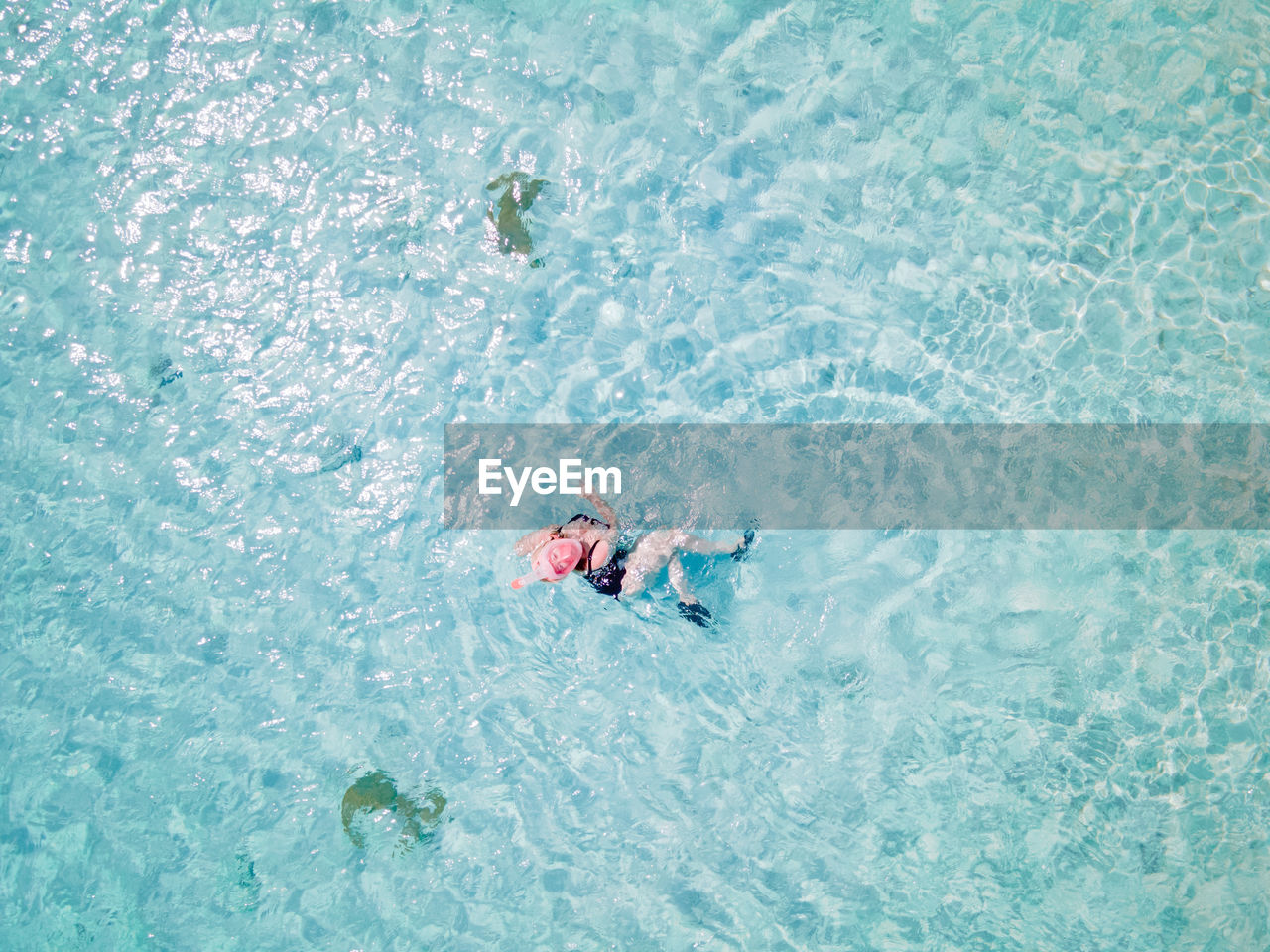 HIGH ANGLE VIEW OF YOUNG MAN SWIMMING IN POOL