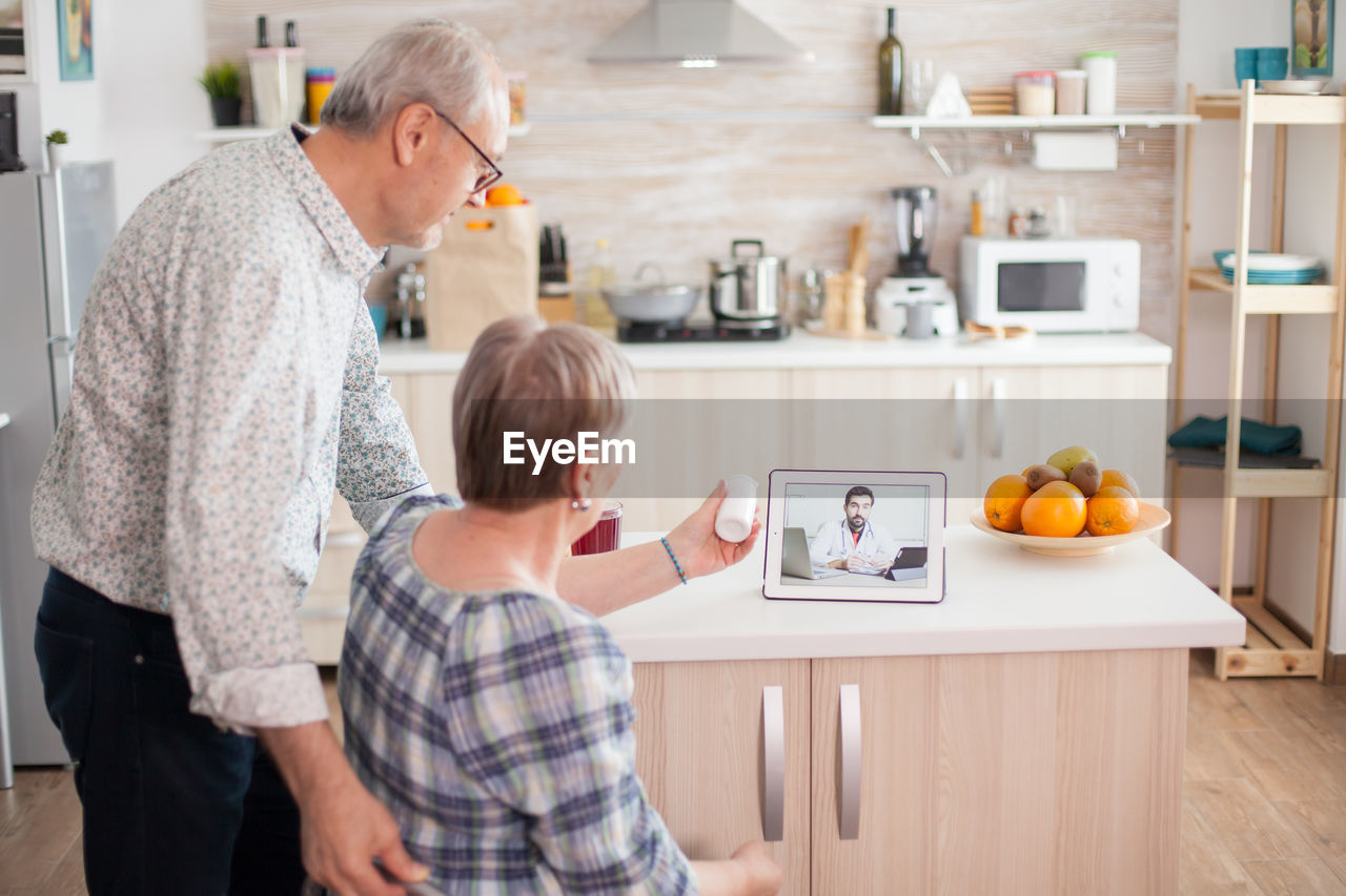 Rear view of couple talking with doctor on video call