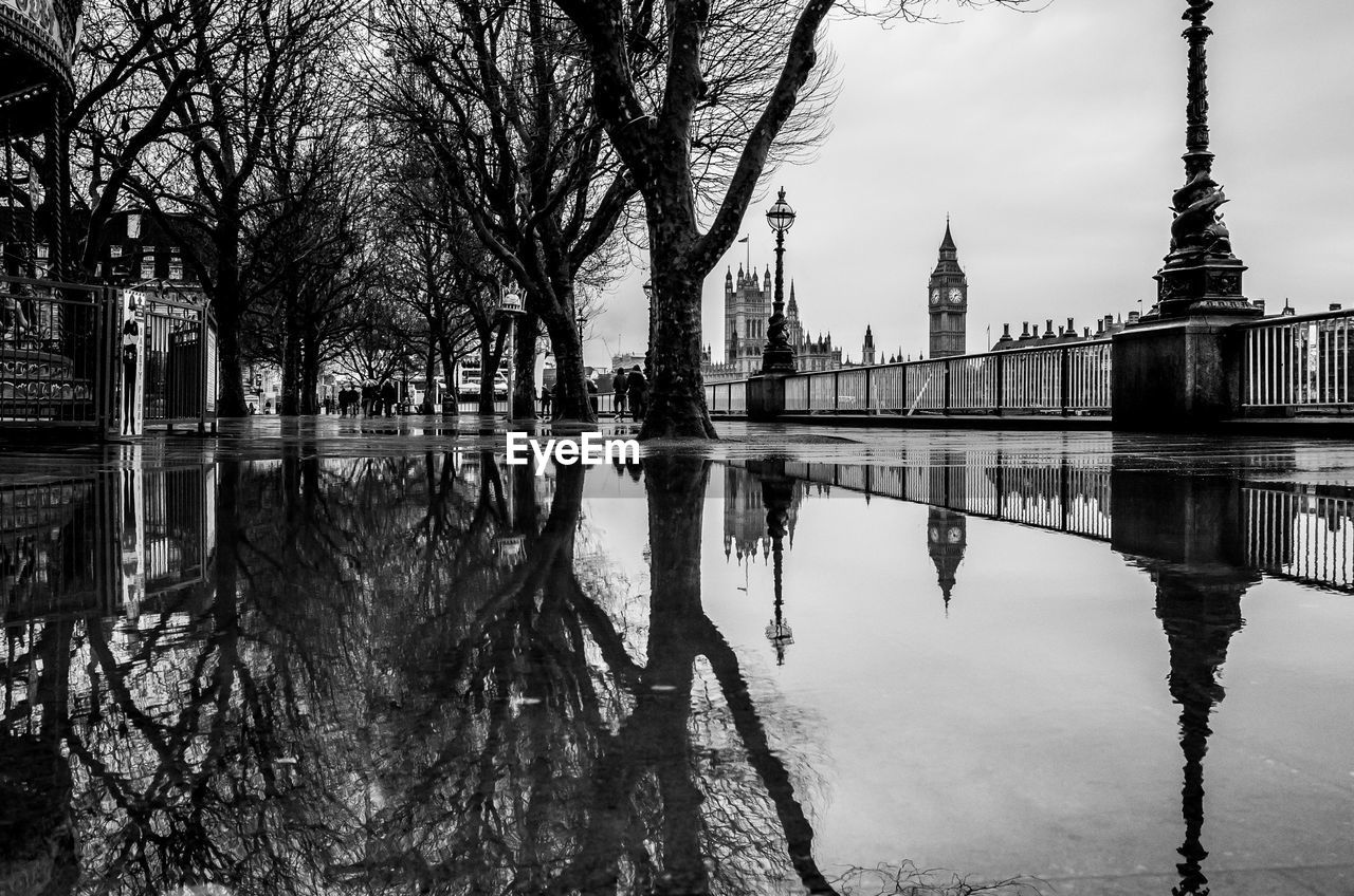 Reflection of bare trees in puddle against big ben