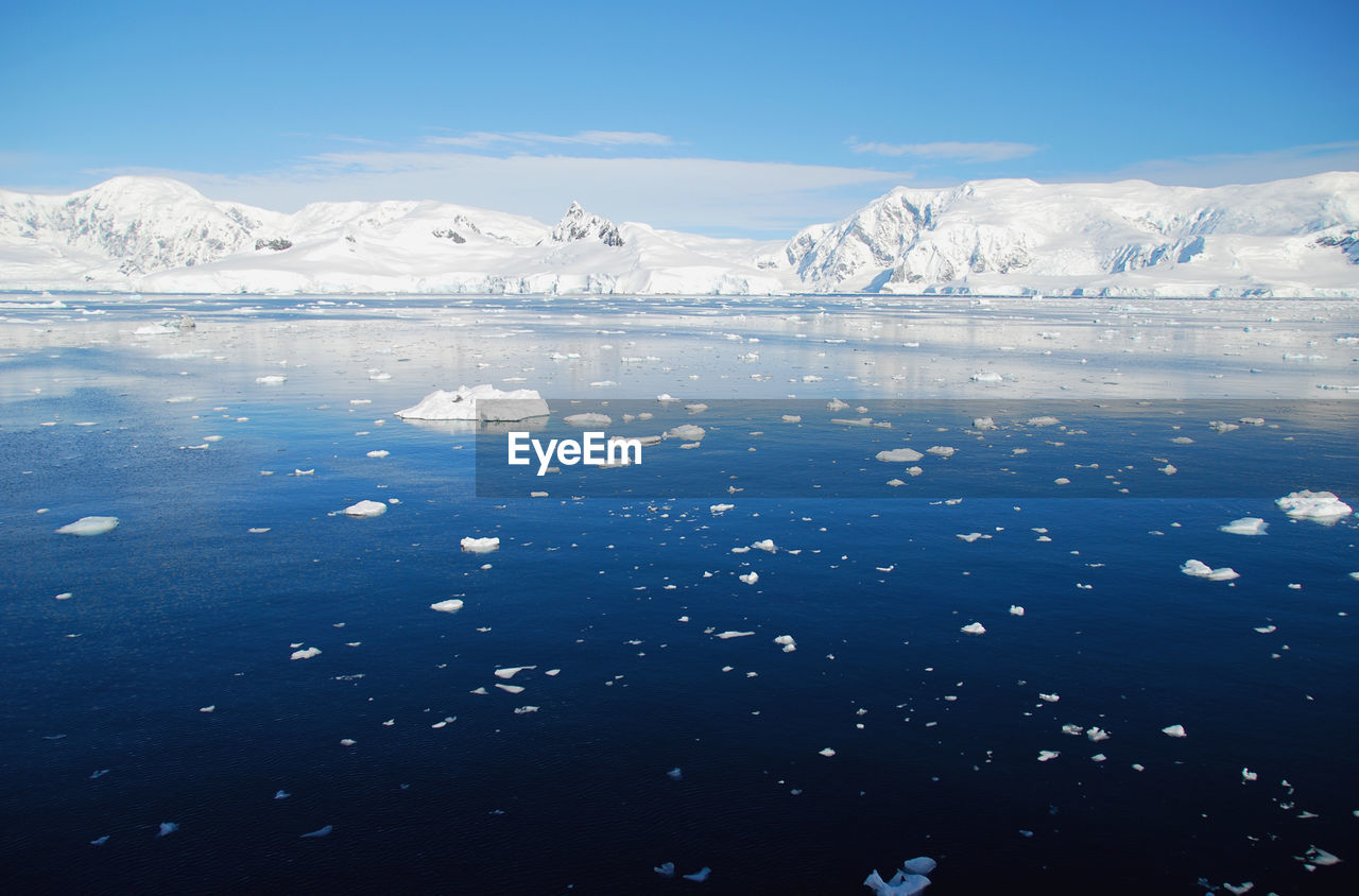 Scenic view of snowcapped mountains against blue sky