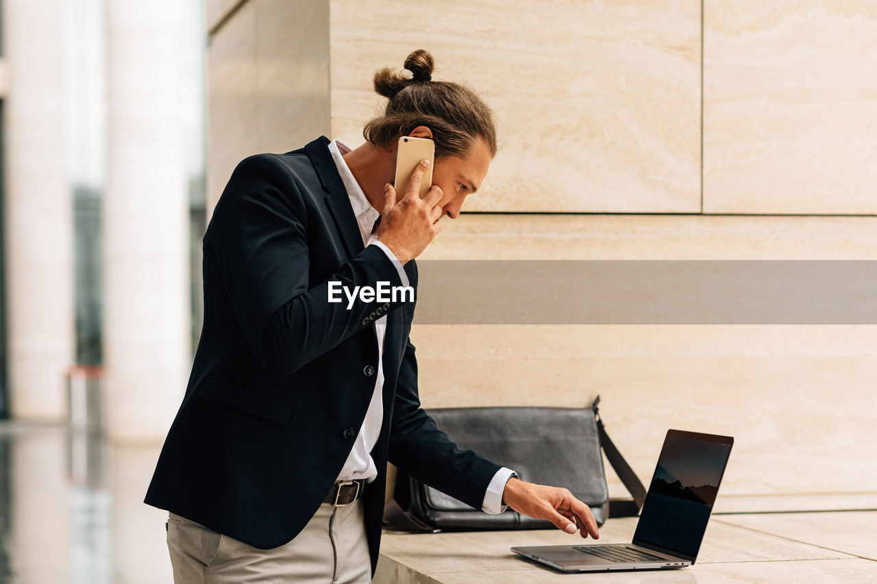 Businessman using laptop while talking on phone