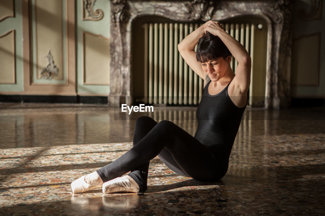 Ballerina tying hair bun in studio