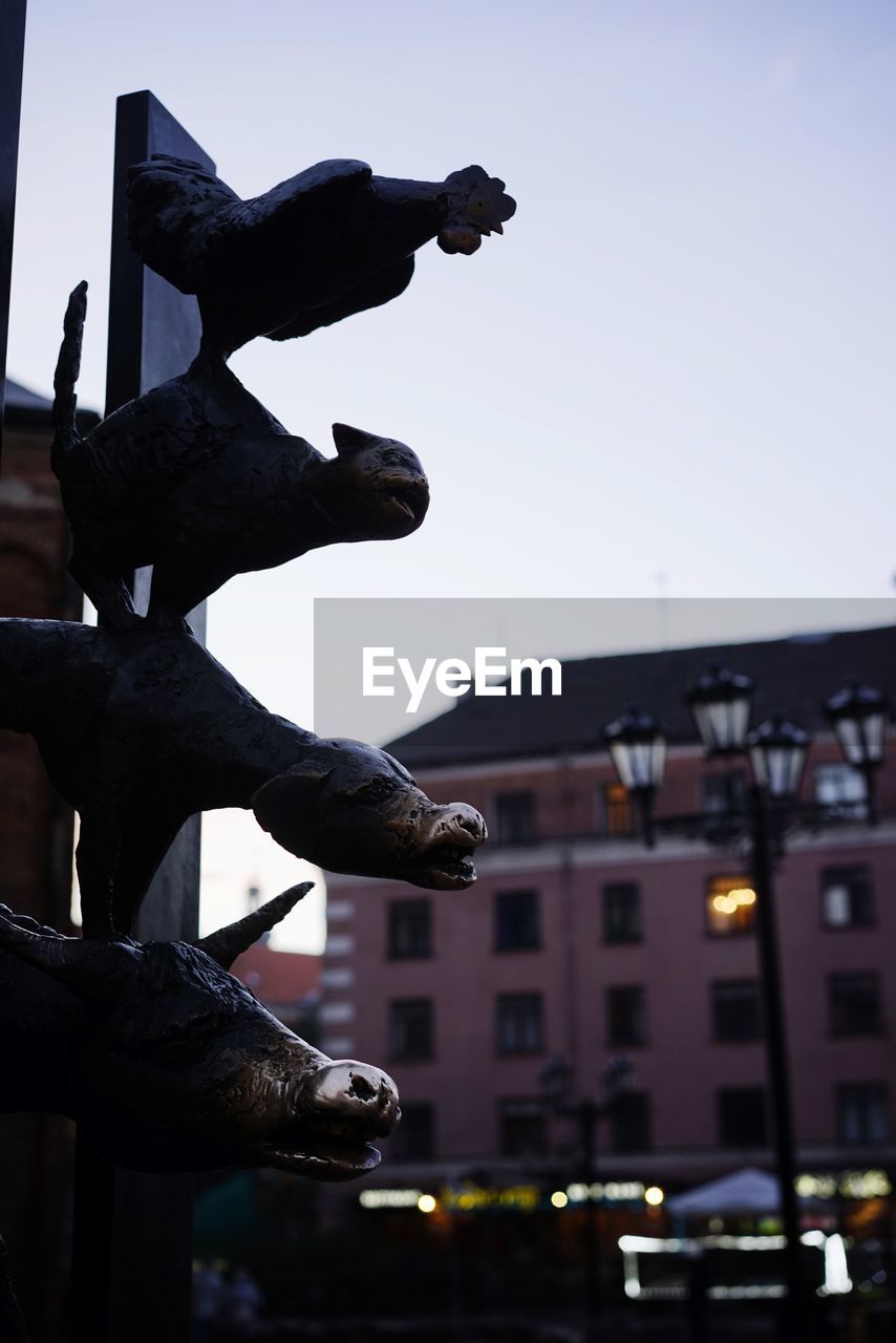 LOW ANGLE VIEW OF STATUE AGAINST ILLUMINATED BUILDING AGAINST SKY