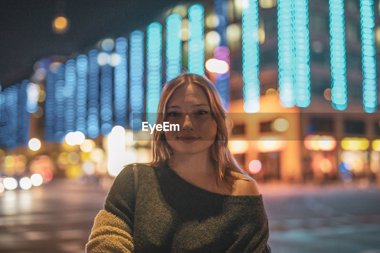 Fashionable young woman in city at night