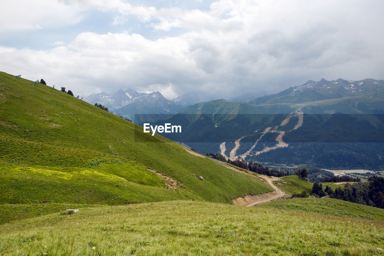 Green slope of a high mountain during a thunderstorm with clouds in the sky