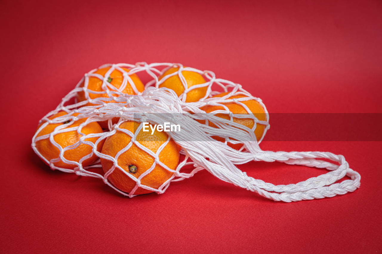 Eco-friendly mesh with tangerines on a red festive background. feast of the nativity of christ.