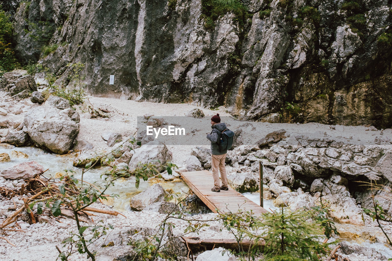 Rear view of man standing on footbridge against mountain