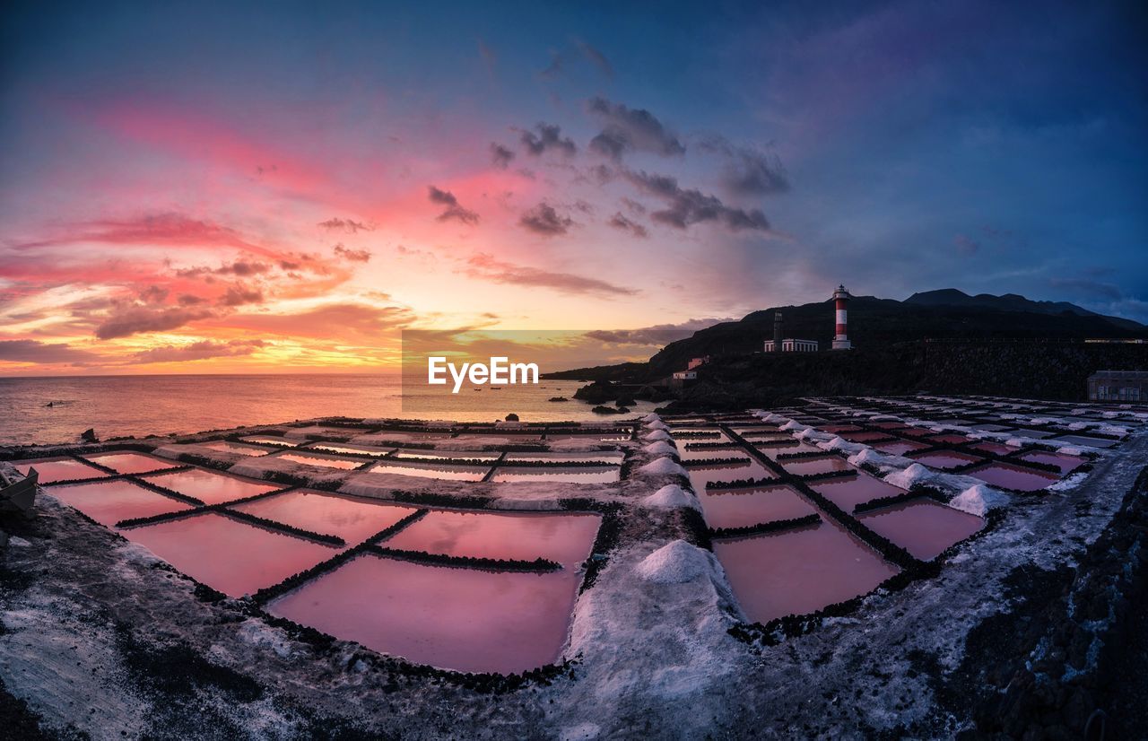 High angle view of salt flats by sea against cloudy sky during sunset