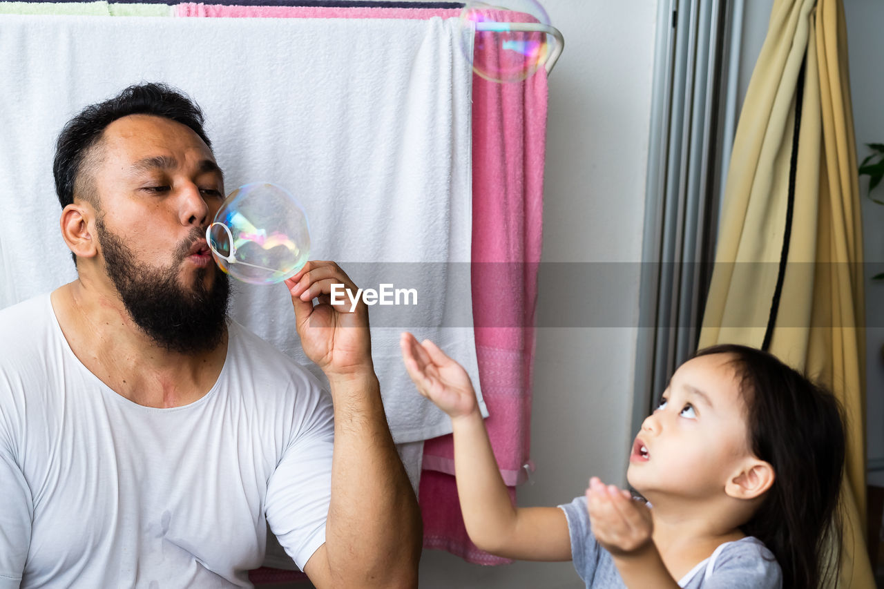 Girl playing father blowing bubbles