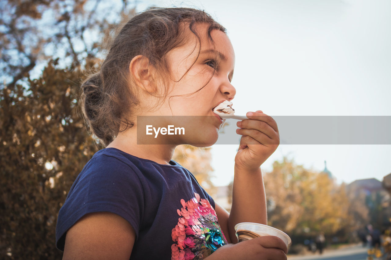 Close-up of girl having ice cream while standing outdoors