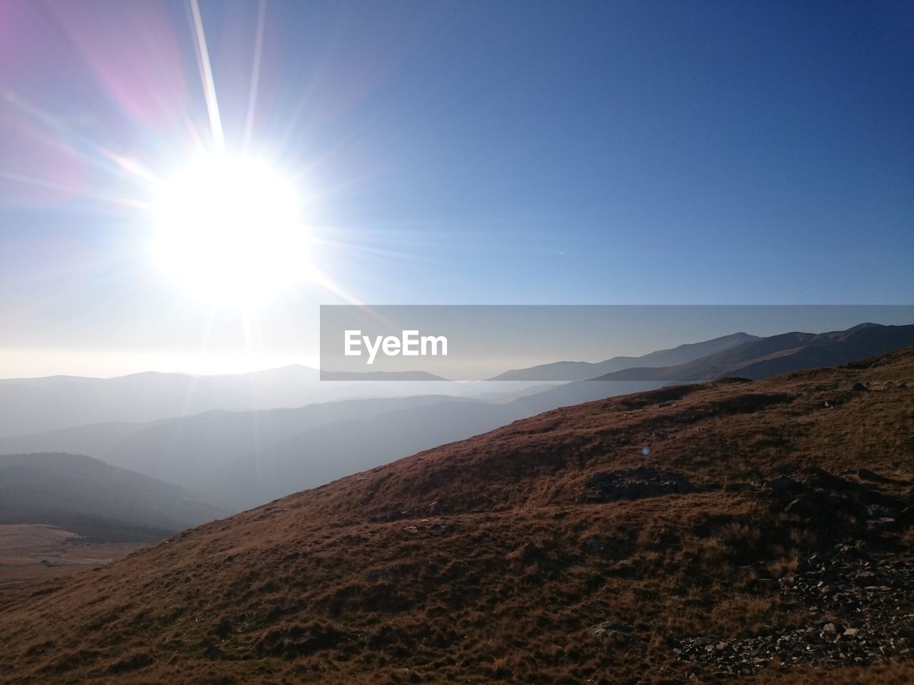 SUN SHINING THROUGH CLOUDS OVER MOUNTAINS