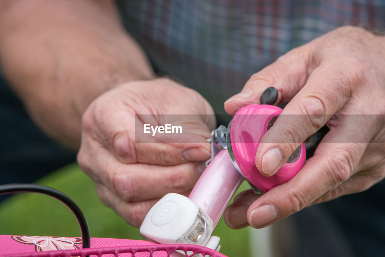 Close-up of hands adjusting bell on bicycle handle