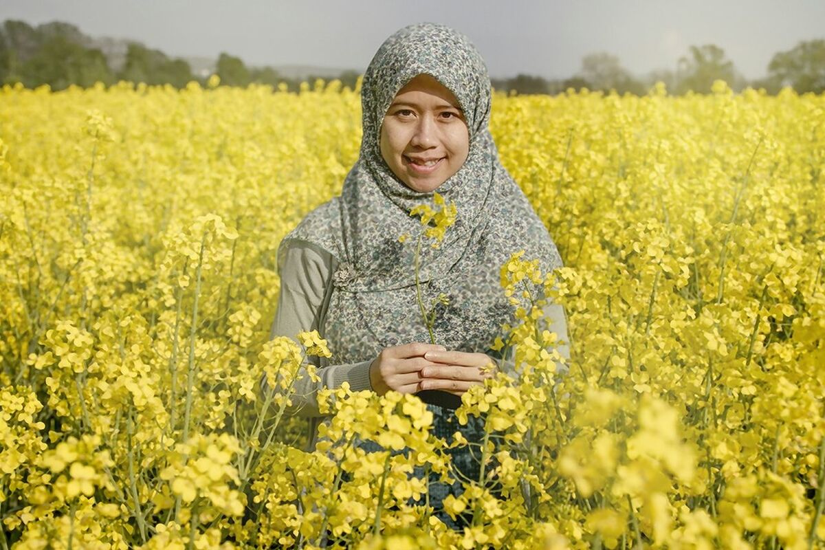 Portrait on smiling woman standing on oilseed rape field