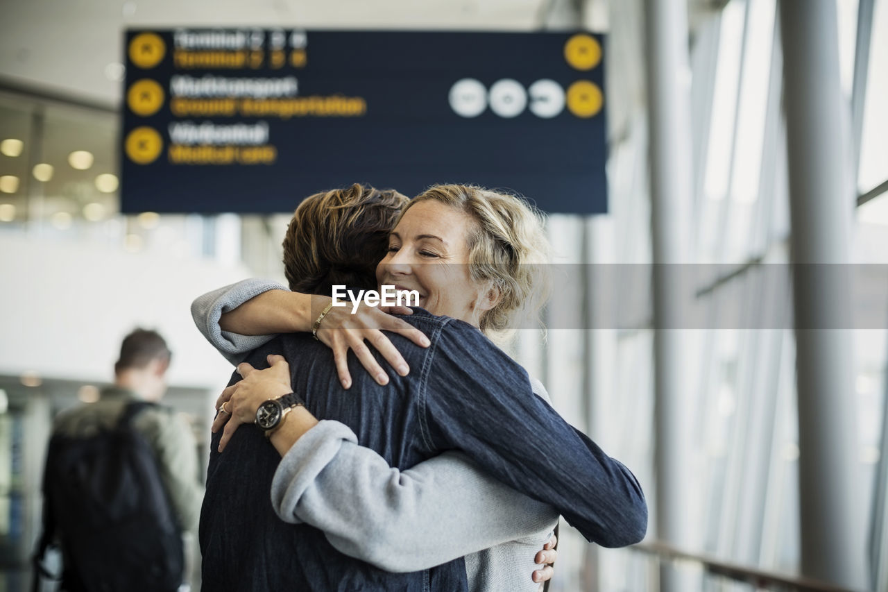 Happy businesswoman embracing male colleague at airport