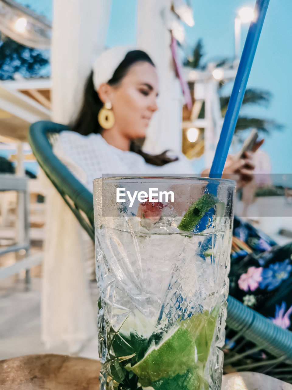 Selective focus of refreshing cocktail on table in bar and young woman in background.