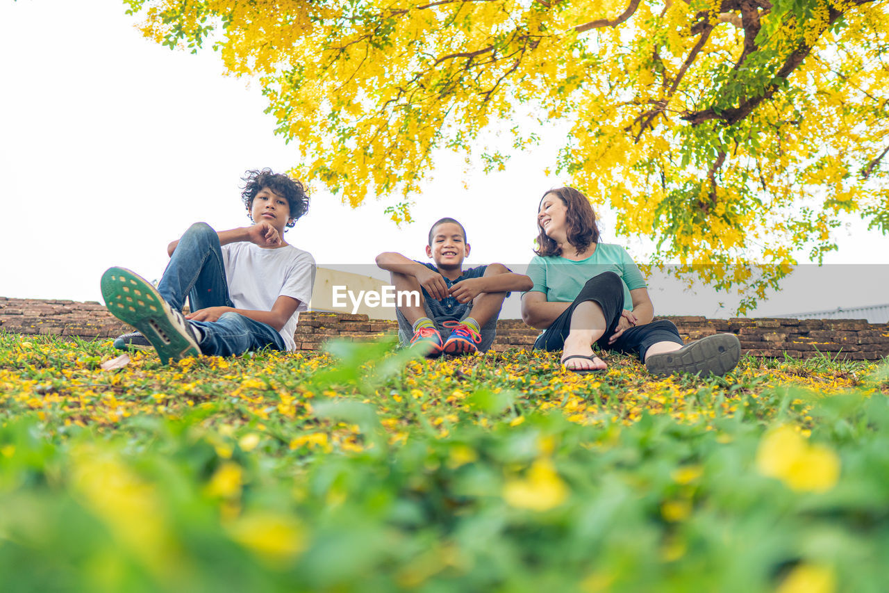 FULL LENGTH OF YOUNG COUPLE SITTING ON ROCK