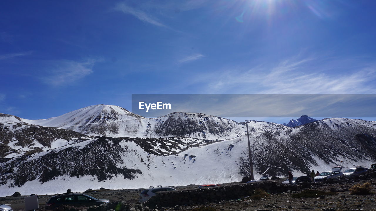 Scenic view of snowcapped mountains against blue sky