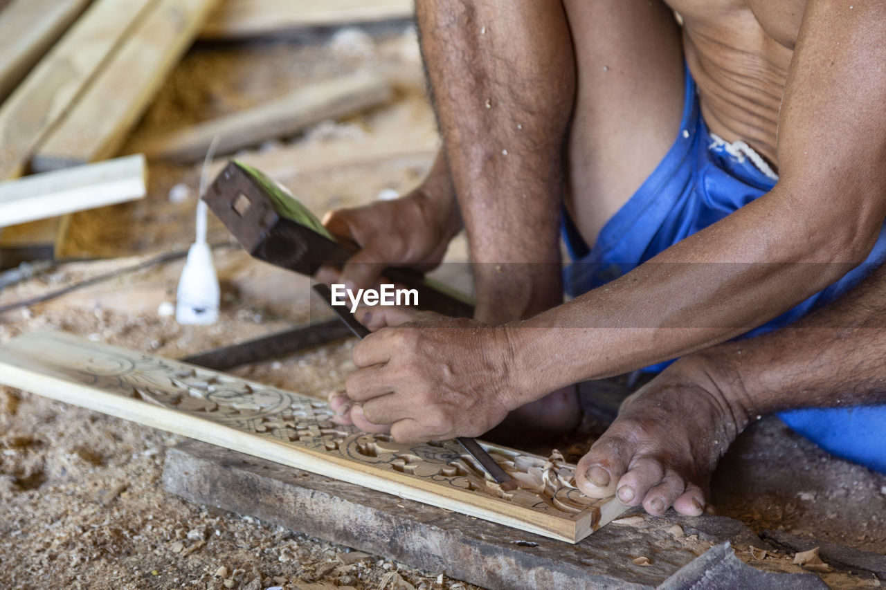 Midsection of man carving wood