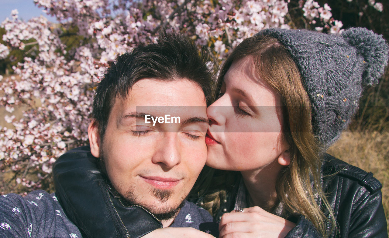 Close-up of girlfriend kissing boyfriend while sitting at park