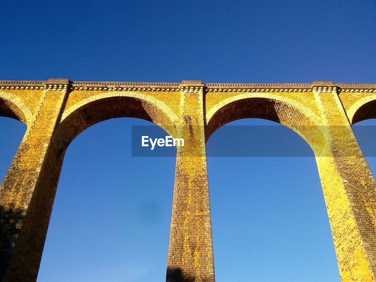 Low angle view of arched structure against blue sky