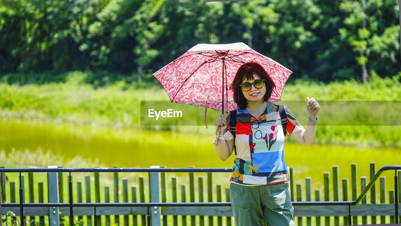 Full length of man holding umbrella standing on sunny day