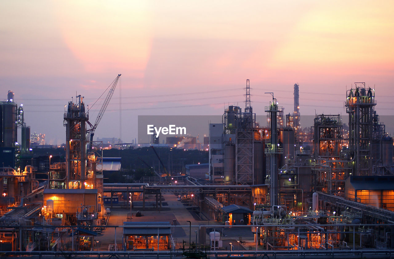 Illuminated factory against sky during sunset