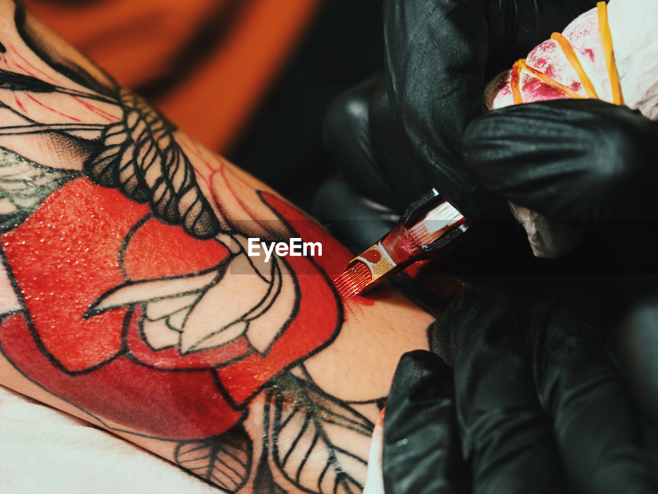 Cropped image of female artist making tattoo on male customer hand