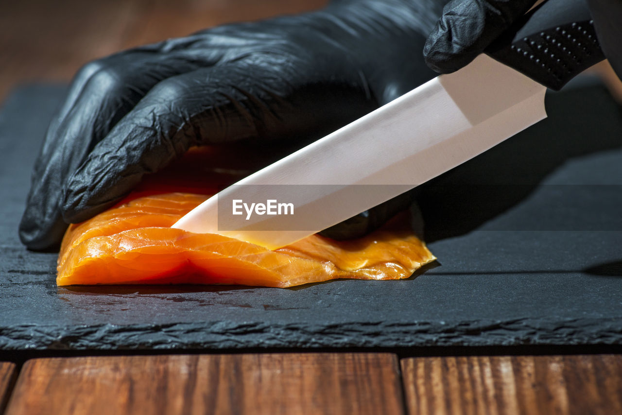 cropped hand of man holding knife on cutting board