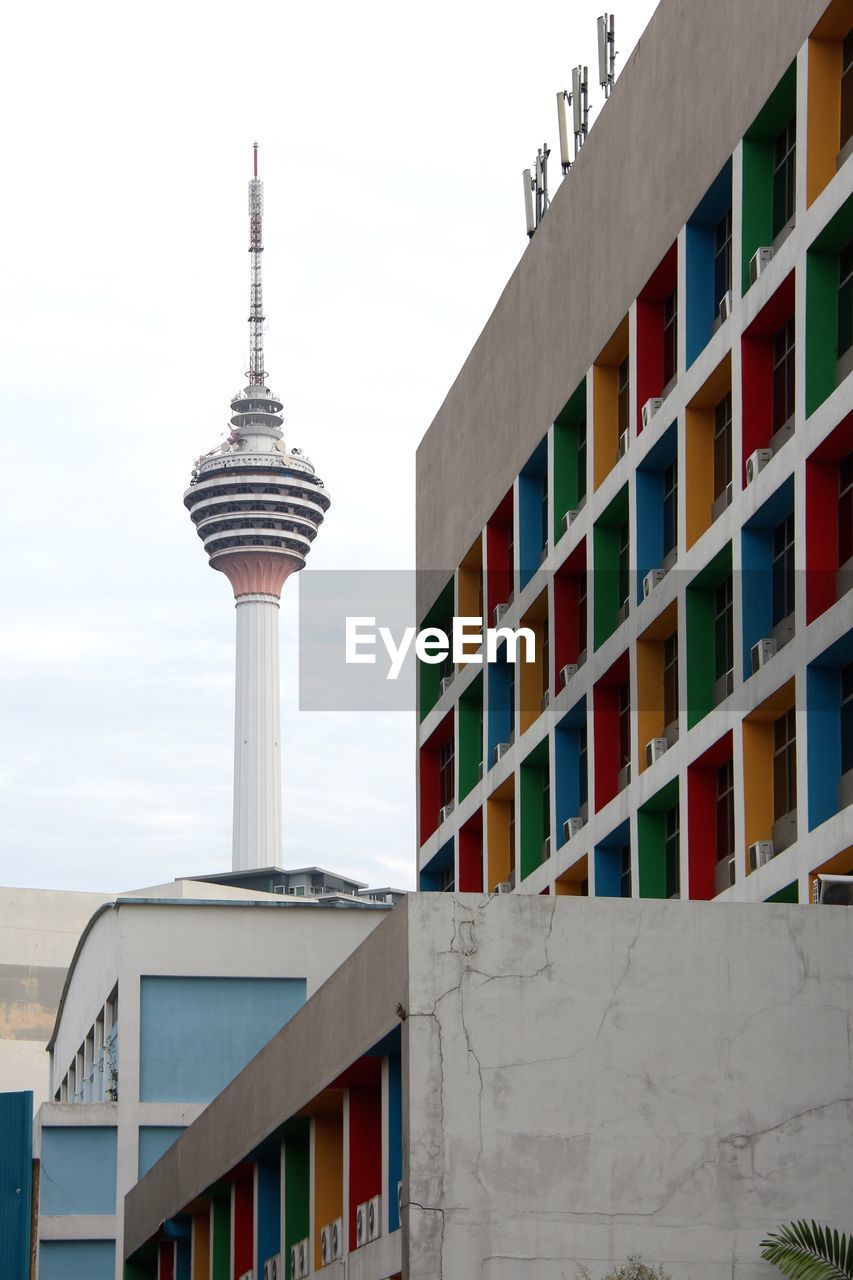 Low angle view of multi colored building by tower against sky